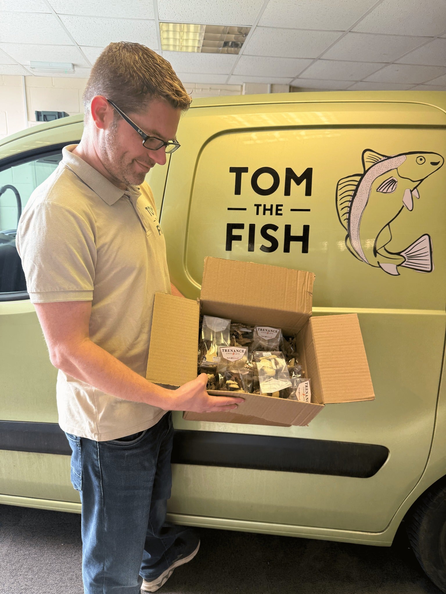Tom the Fish in front of his Van holding a box of chocolates