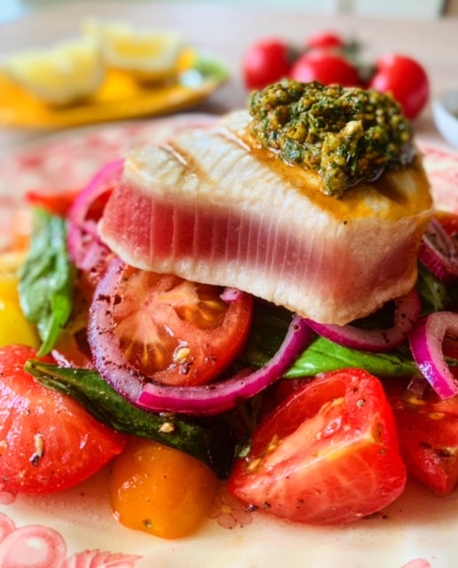 Cooked yellowfin tuna loin on bed of tomatoes basil and onions