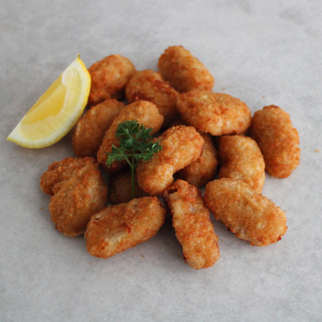 A plate of breaded scampi tails with a slice of lemon and parsley garnish.